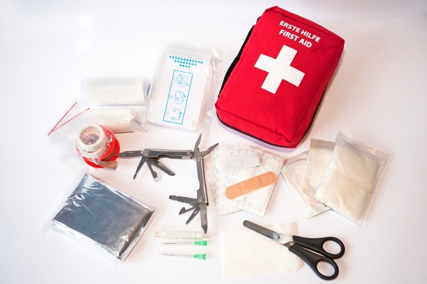 Open first aid kit with bandages, scissors, "triangle scarf", syringe, plaster, knife, tools, gauze, etc
