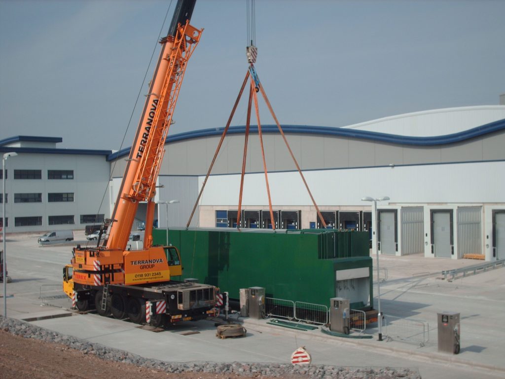 Orange Crane lowering a green custom filling station at home bargains warehouse