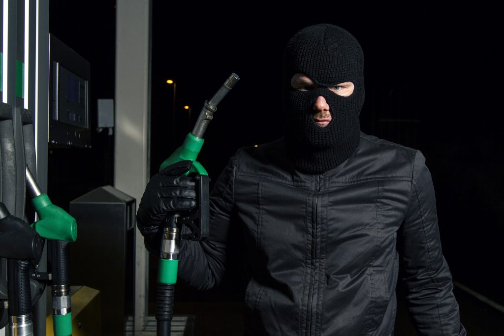 masked man using gas pump